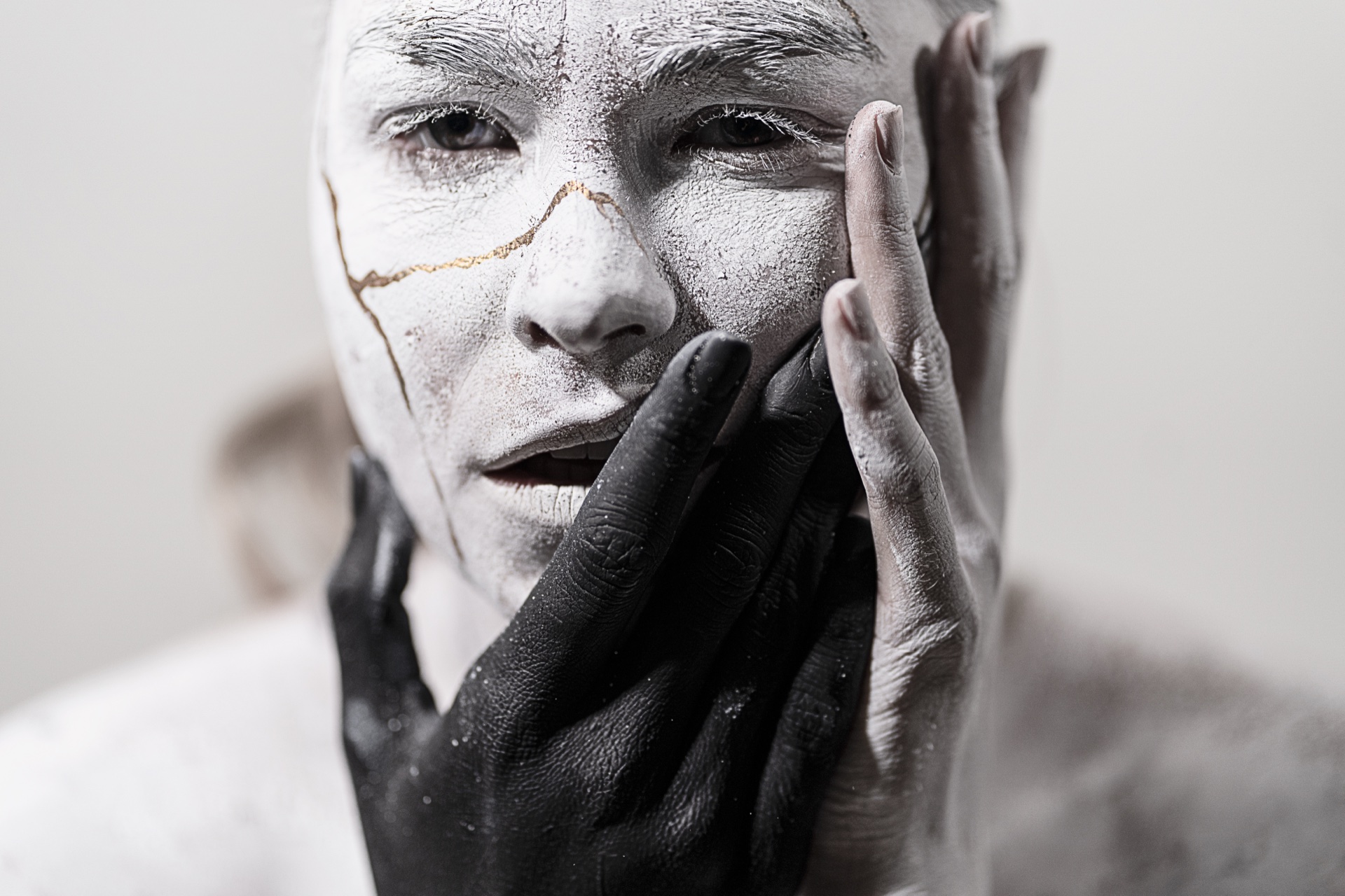 Black painted hand pressed against the sculptural figure's white concrete-textured face