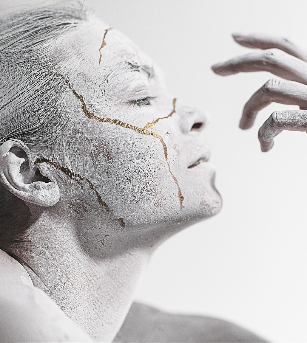 Sculpted profile portrait threaded with gold kintsugi cracks running across the cheek and temple