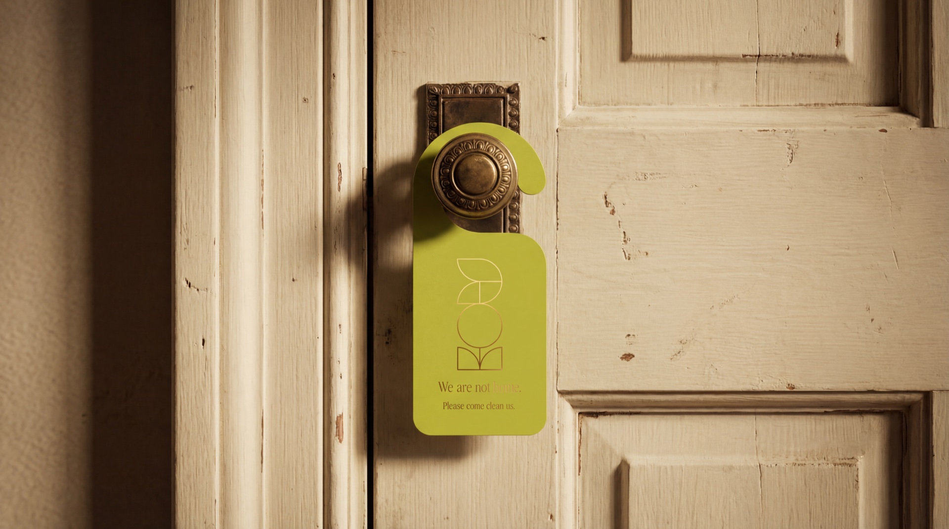 Lime-green Valeria's House do-not-disturb door hanger reading 'We are not, please come clean us', hung on a vintage brass door knob