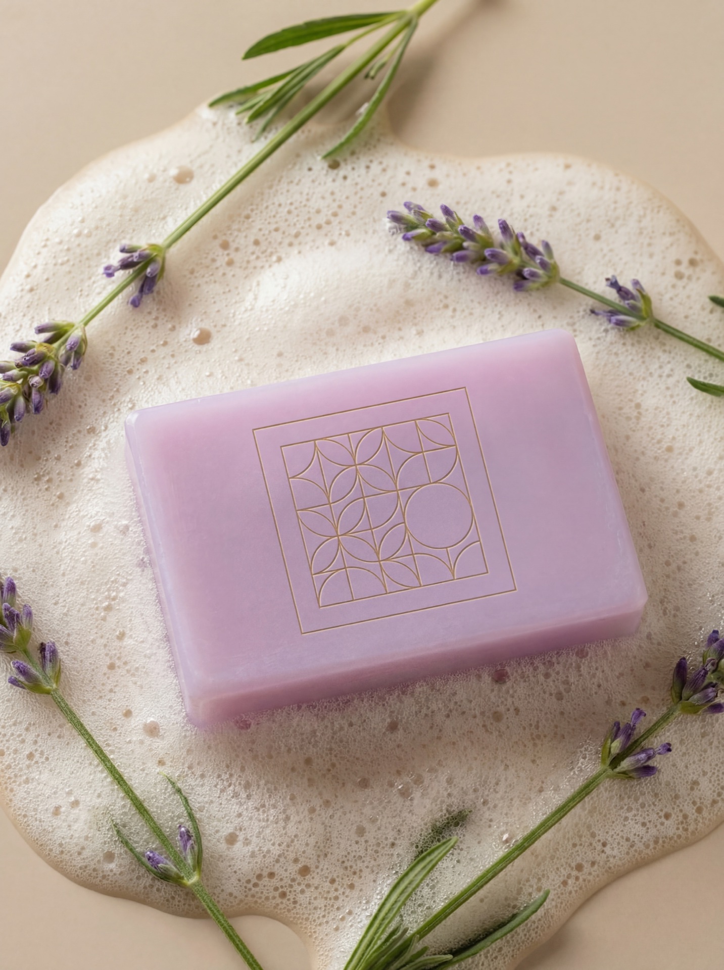 Lilac lavender soap bar embossed with the Valeria's House geometric crest, resting on a soap-foam puddle with fresh lavender sprigs