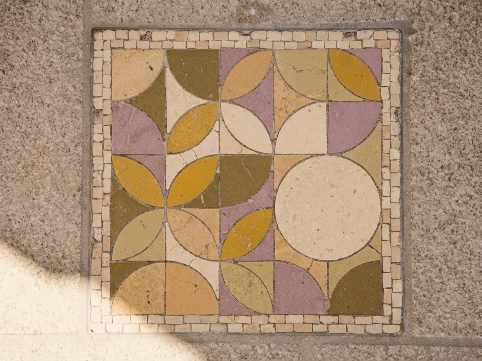 Hand-set stone mosaic tile of the Valeria's House crest installed in the property courtyard floor — the physical counterpart to the digital logo
