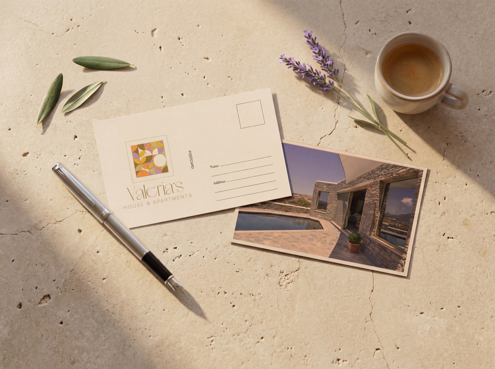 Valeria's House postcard with a mosaic stamp and an island view print, laid on cracked limestone with espresso, lavender and olive leaves